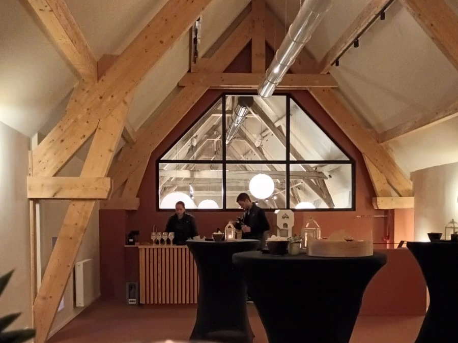 Salle de cocktail dînatoire avec bar, tables hautes, espace lounge, scène et installation audio pour 90 personnes